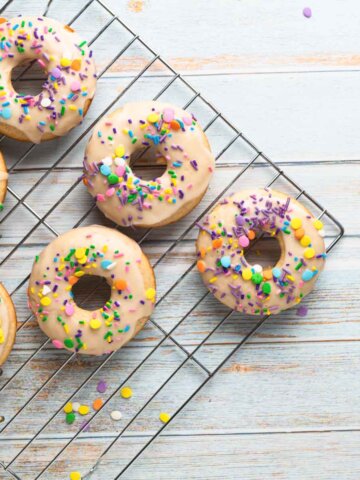 baked vanilla donuts with sprinkles on a baking rack