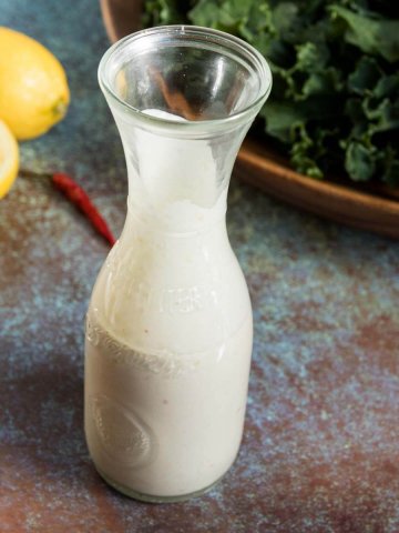 cream lemon tahini dressing with freshly squeezed lemons in the background