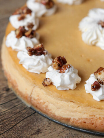 maple cheesecake with maple whipped cream and maple glazed pecans on a table